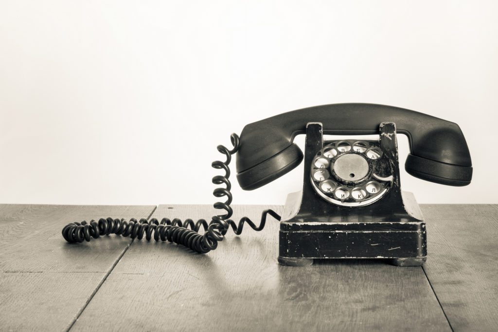 Vintage telephone on old table sepia photo