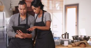 Small business owner showing employee new plan on tablet computer