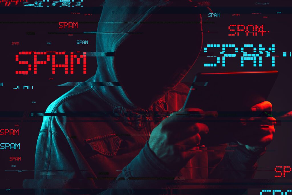Electronic spamming concept with faceless hooded male person using tablet computer, low key red and blue lit image and digital glitch effect