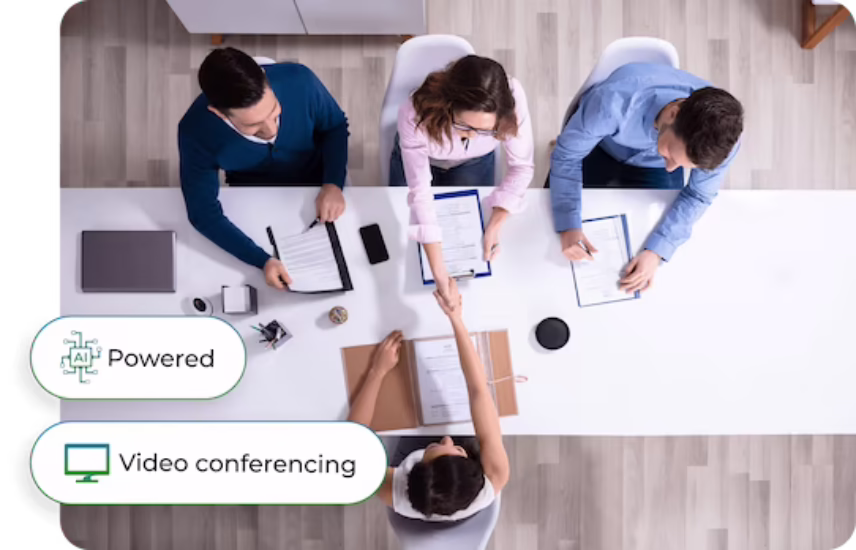 Overhead view of recruiters reviewing candidate documents around a conference table, with Phone.com AI-powered video conferencing feature callouts